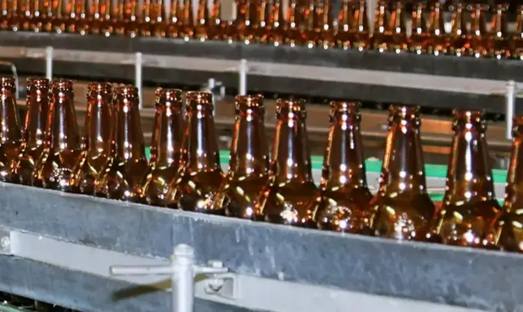 a row of brown bottles on a conveyor belt