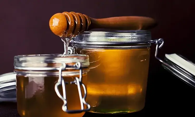 a jar of honey with a wooden dipper